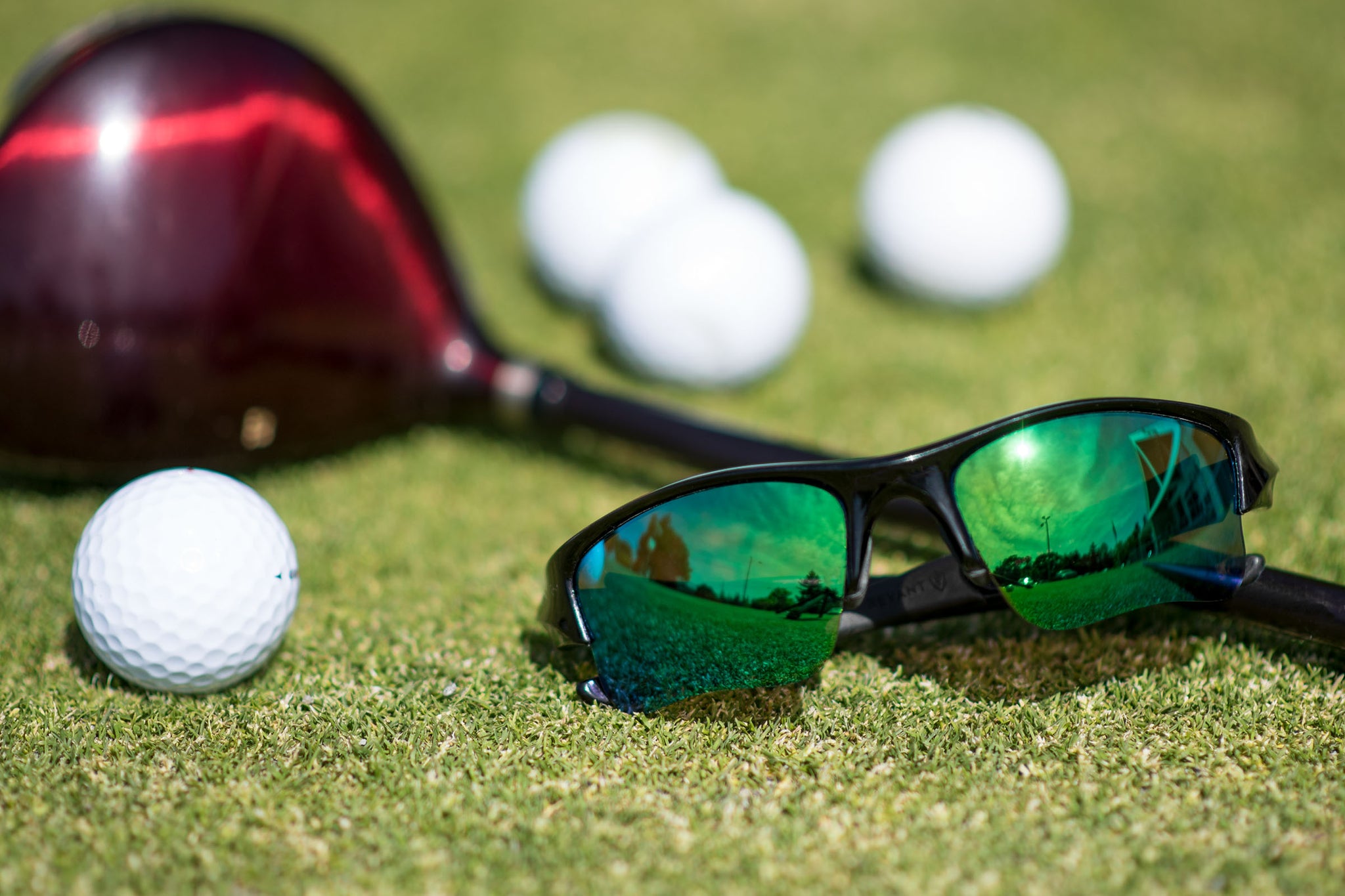 Oakley Flak Jacket XLJ sunglasses with Emerald Green replacement lenses on a golf course with clubs and golf balls