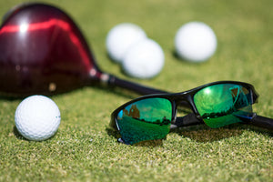 Oakley Flak Jacket XLJ sunglasses with Emerald Green replacement lenses on a golf course with clubs and golf balls