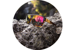 View of a pair of sunglasses with midnight sun replacement lenses sitting on a rock.