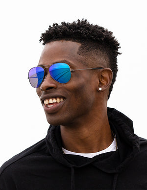 Shoulders-up view of a model with short, dark hair smiling and wearing sunglasses with Ice blue sunglass lenses.
