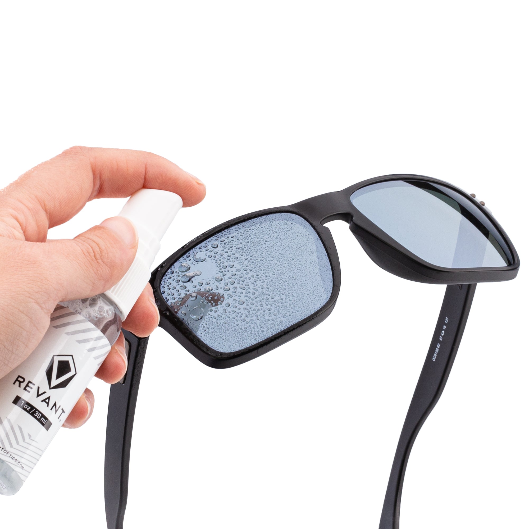 A hand spraying Revant Lens Cleaner onto a pair of frames.