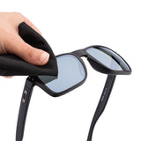 A hand using a microfiber cloth to wipe solution off the sunglasses' lens.